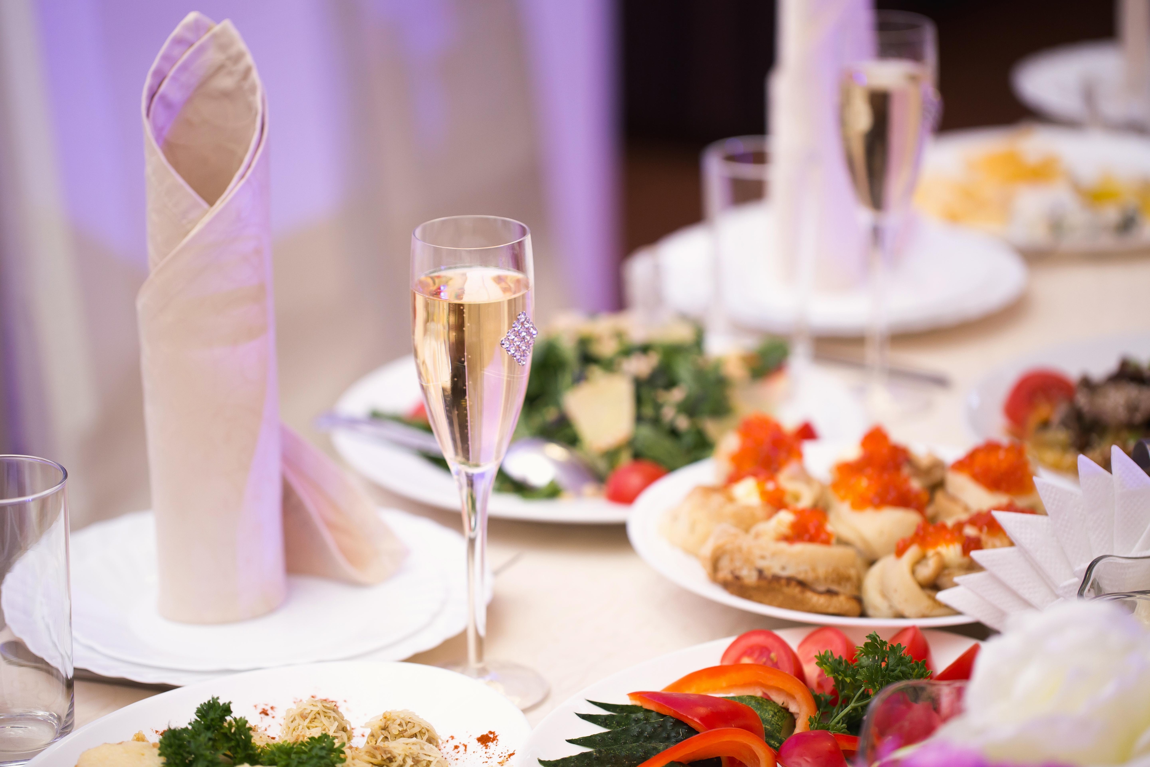 Festtafel mit Sekt, kunstvollen Servietten und Tellern mit Vorspeisen wie Salaten und Canapés.