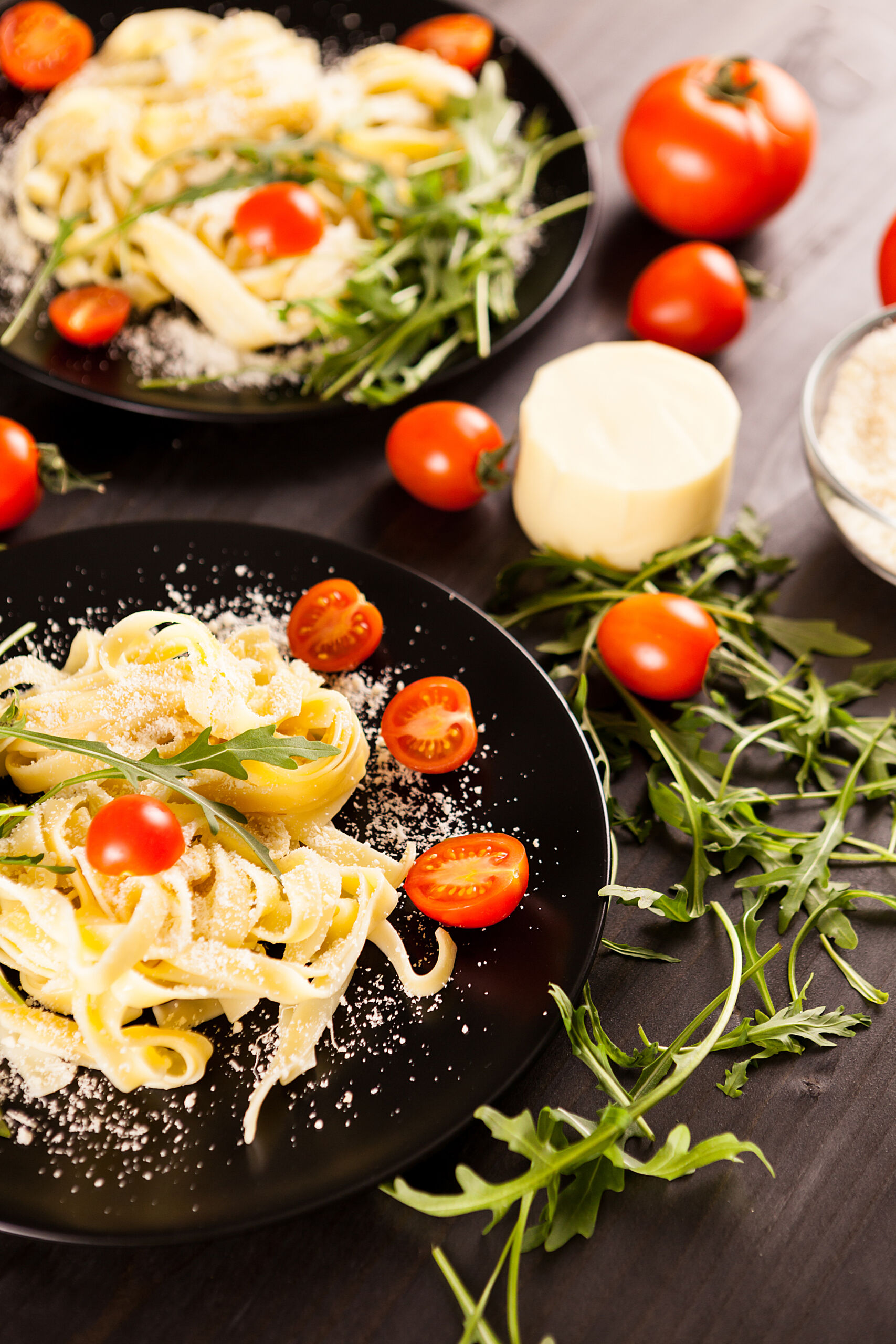 Tagliatelle pasta with parmesane, lettuce and cherry tomatoes on wooden table