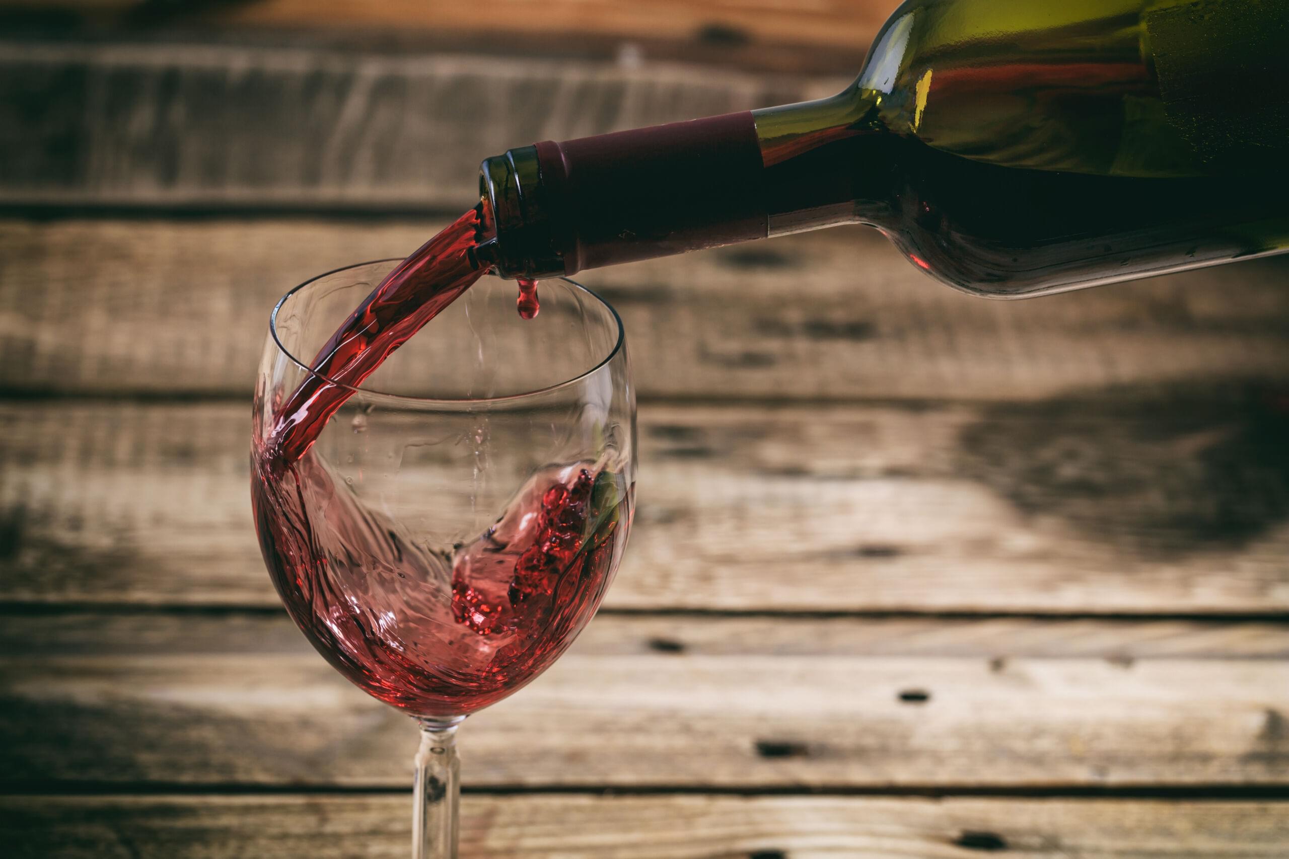 Pouring wine into a glass from a bottle.